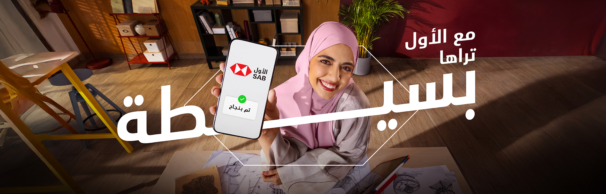 مصممة أزياء سعودية في مكتبها تعرض هاتفها مكتوب عليه كلمة "بسيطة" باللغة العربية