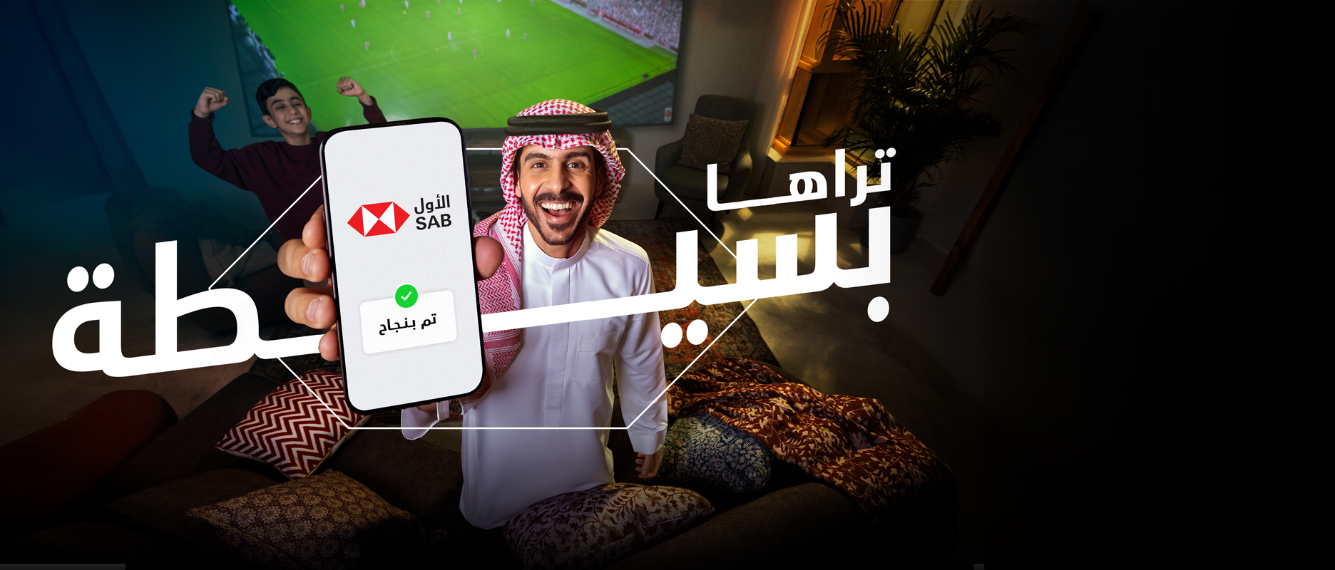 رجل سعودي في ملعب كرة قدم يُظهر هاتفه مكتوب عليه كلمة "قاعدة" باللغة العربية