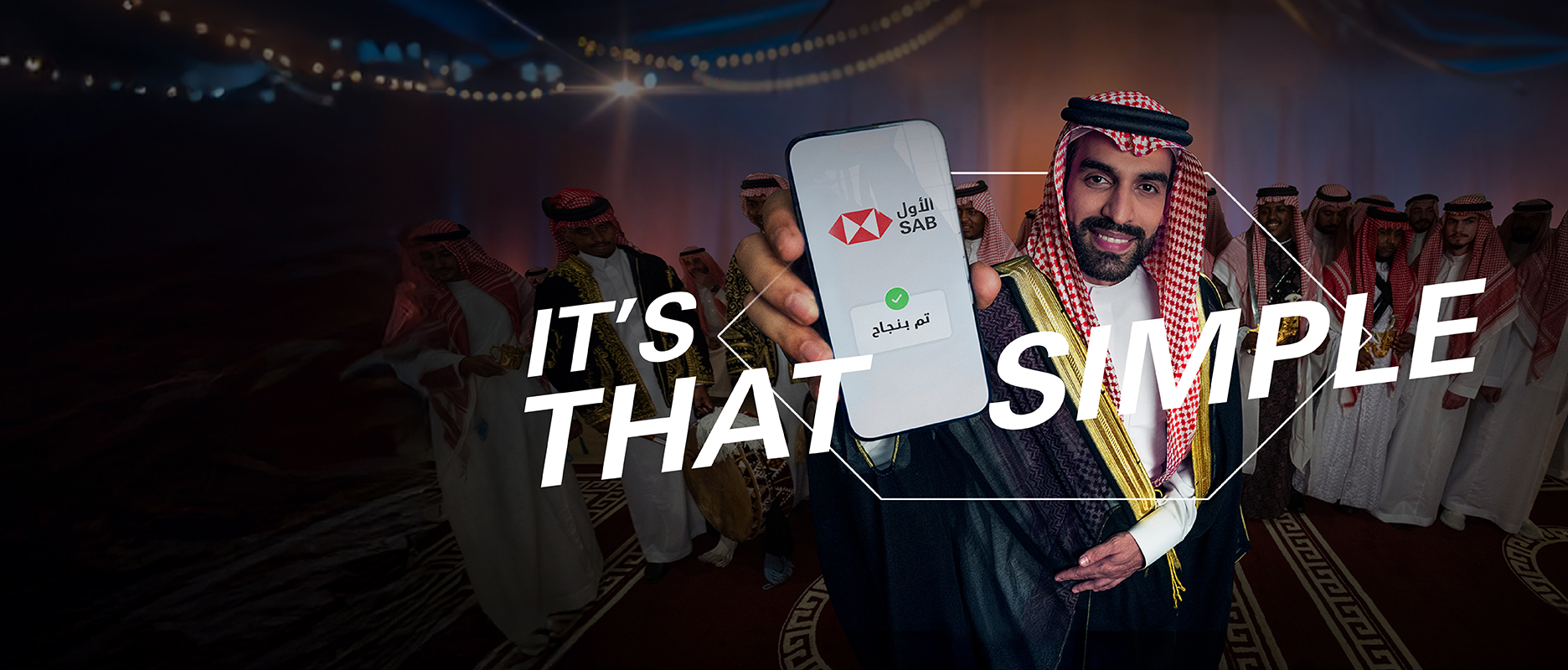 a saudi groom in a saudi wedding showing his phone with the word simple in arabic